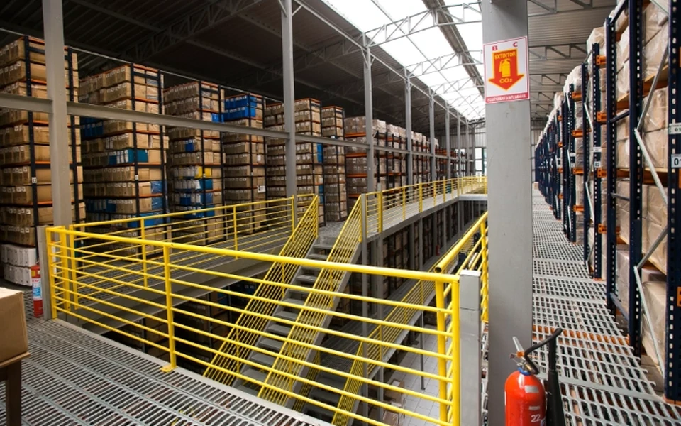 A document warehouse shown on Multi Stock's website: shelves packed with boxes surround a metal walkway with yellow safety rails.